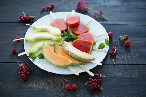 Teller mit hausgemachten Wassermelonen-Eislutschern, Scheiben von Galia- und Cantaloupe-Melone, lizenzfreies Stockfoto