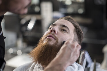 Friseur bürstet Kunden die Seitenhaare im Friseursalon - ZEF009221