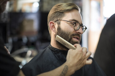 Friseur kämmt den Bart eines Kunden - ZEF009223