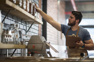 Man reaching out for a jar in distillery - ZEF009251