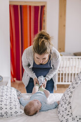 Mutter und kleiner Junge, auf dem Bett liegend, beim Anziehen - HAPF000656