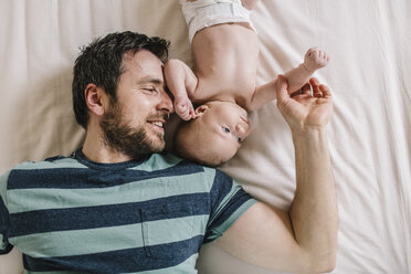 Father with baby boy lying on bed at home - HAPF000663