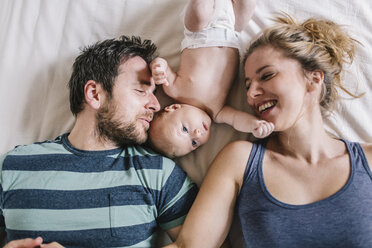 Mutter und Vater mit einem kleinen Jungen auf dem Bett liegend - HAPF000666