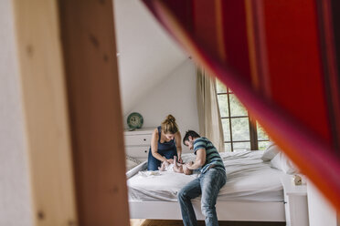 Mutter und Vater mit einem kleinen Jungen im Bett - HAPF000671