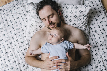 Father with baby boy lying on bed at home - HAPF000672