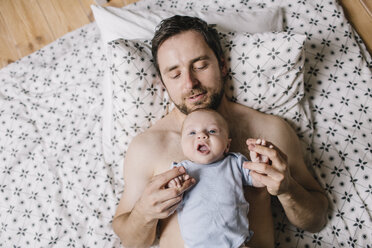 Father with baby boy lying on bed at home - HAPF000673