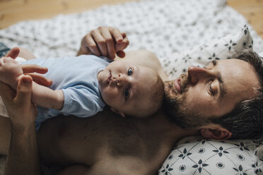 Father with baby boy lying on bed at home - HAPF000674