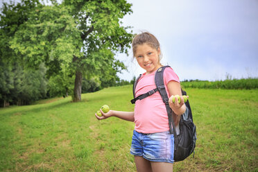 Smiling girl collecting apples on a meadow - VTF000535