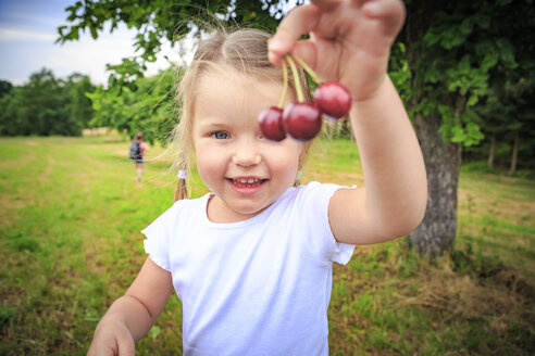 Happy little girl showing cherries - VTF000536