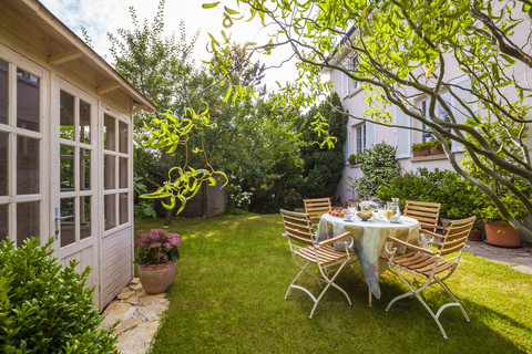 Gartenhäuschen und gedeckter Tisch im Garten, lizenzfreies Stockfoto