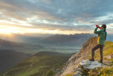 Österreich, Tirol, Wanderer trinken, Sonnenuntergang - MKFF000317