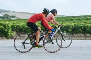 Spanien, Andalusien, Jerez de la Frontera, Pärchen auf Fahrrädern auf einer Straße zwischen Weinbergen - KIJF000620