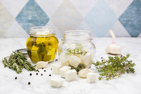 Glas gewürfelter Schafskäse, eingelegt in Olivenöl, Thymian, Knoblauch, Pfeffer und Rosmarin, lizenzfreies Stockfoto