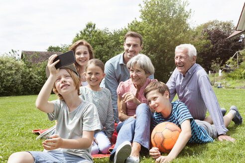 Boy taking selfie of happy extended family in garden - RBF004761