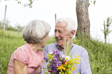 Happy senior couple with bunch of flowers outdoors - RBF004769