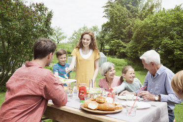 Happy extended family dining in garden - RBF004776