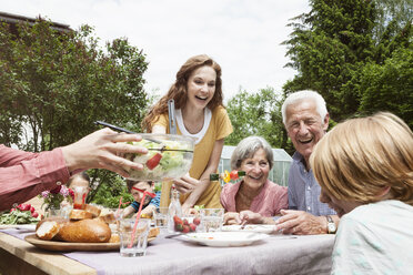 Glückliche Großfamilie beim Essen im Garten - RBF004780