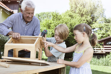 Großvater und Enkelkinder bauen ein Vogelhaus - RBF004794