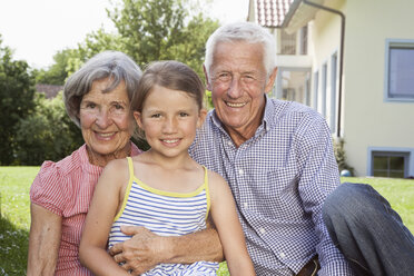 Porträt von glücklichen Großeltern mit Enkelin im Garten - RBF004801