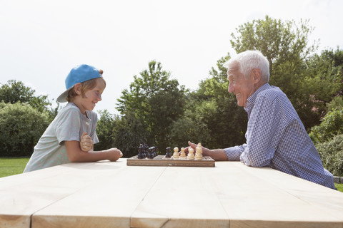 Grandfather and grandson playing chess in garden stock photo