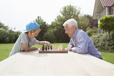 Großvater und Enkel spielen Schach im Garten - RBF004804