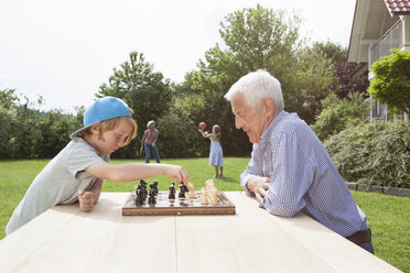 Grandfather and grandson playing chess in garden - RBF004805