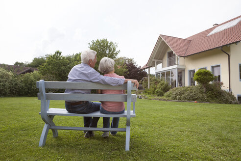 Älteres Paar sitzt auf einer Bank im Garten - RBF004815