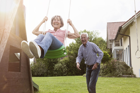 Playful senior couple with swing in garden stock photo