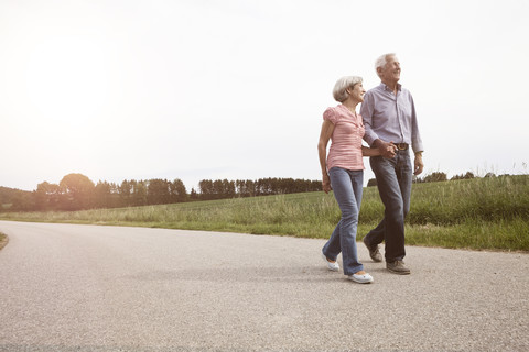 Smiling senior couple walking on country road stock photo