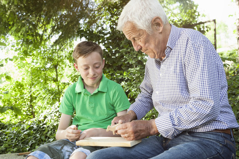 Grandfather and grandson carving together stock photo