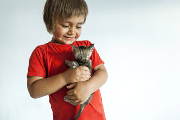 Porträt eines lächelnden kleinen Jungen, der ein Kätzchen hält - VABF000720