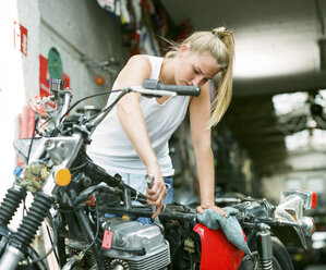 Junge Frau bei der Reparatur eines Motorrads - MADF001032