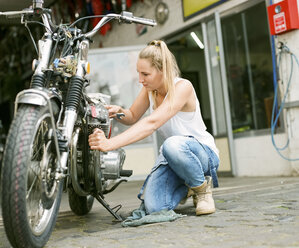 Junge Frau bei der Reparatur eines Motorrads - MADF001034