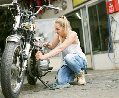 Junge Frau bei der Reparatur eines Motorrads - MADF001034