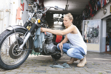 Junge Frau beim Reinigen eines Motorrads - MADF001036