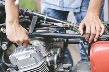 Nahaufnahme einer Frau bei der Reparatur eines Motorrads - MADF001039