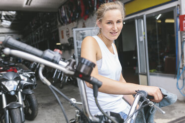 Lächelnde junge Frau auf Motorrad - MADF001040