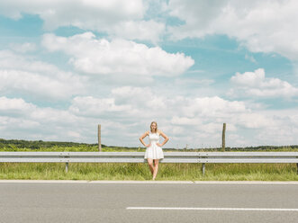 Young woman in white dress standing at the roadside - MADF001052