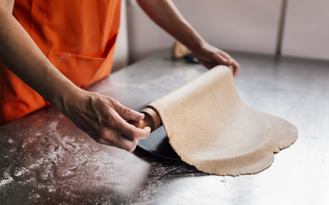 Hände einer Frau beim Ausrollen von Pizzateig, Nahaufnahme, lizenzfreies Stockfoto