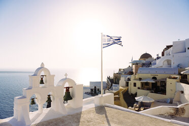 Griechenland, Santorin, griechische Flagge mit Fira im Hintergrund von der  Caldera aus gesehen, lizenzfreies Stockfoto