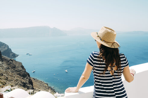 Griechenland, Santorini, Oia, Rückenansicht einer Frau mit Strohhut, die auf das Meer blickt - GEMF000939