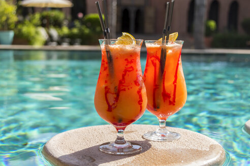 Fruity cocktails floating on swimming pool - JUNF000539