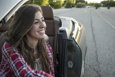 Smiling young woman sitting in convertible - ABZF000880