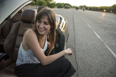 Smiling young woman sitting in convertible - ABZF000886