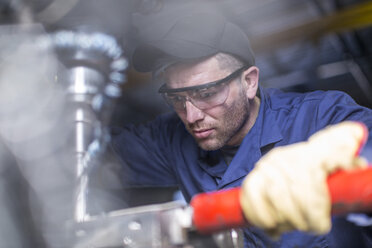 Mechaniker mit Schutzbrille an einer Bohrmaschine in einer Werkstatt - ZEF009298