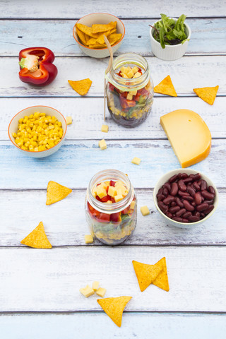 Zwei Gläser mit Tex-Mex-Salat und Zutaten auf Holz, lizenzfreies Stockfoto