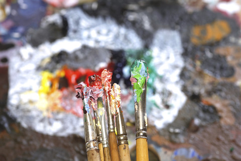 Verschiedene gebrauchte Pinsel vor der Palette eines Künstlers, lizenzfreies Stockfoto