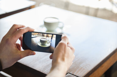 Mann fotografiert mit seinem Handy eine Tasse Kaffee - DIGF000797