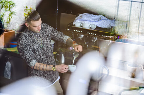 Junger Mann bereitet Kaffee mit Milch in einem Café zu - DIGF000809