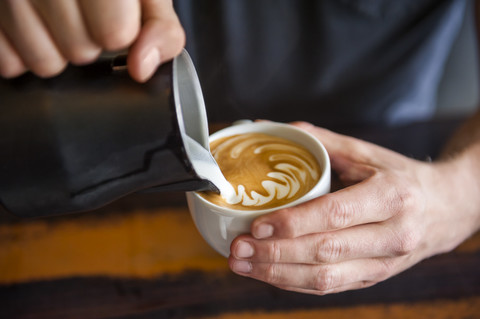 Barista bei der Zubereitung von Cappuccino in einem Kaffeehaus, lizenzfreies Stockfoto